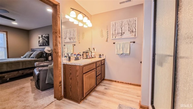 ensuite bathroom with visible vents, vanity, ensuite bath, wood finished floors, and baseboards