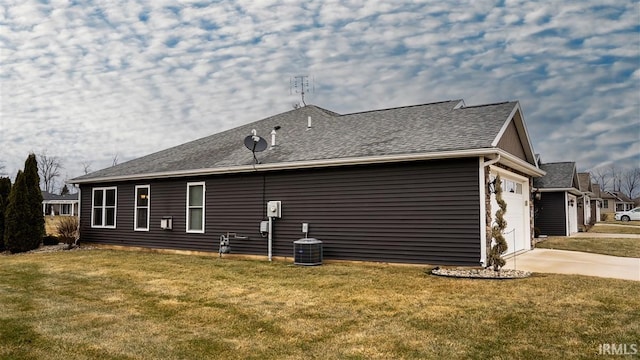 back of house with a shingled roof, cooling unit, concrete driveway, and a yard