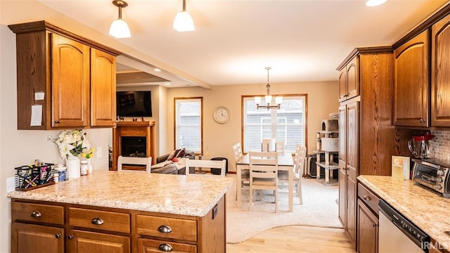 kitchen featuring hanging light fixtures, brown cabinetry, decorative backsplash, and stainless steel dishwasher