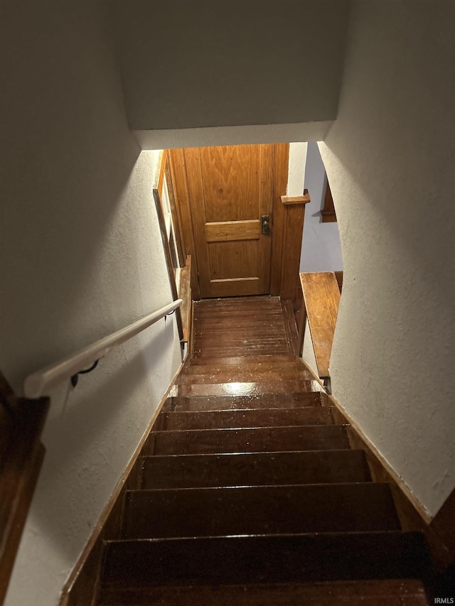 stairs with a textured wall and hardwood / wood-style flooring