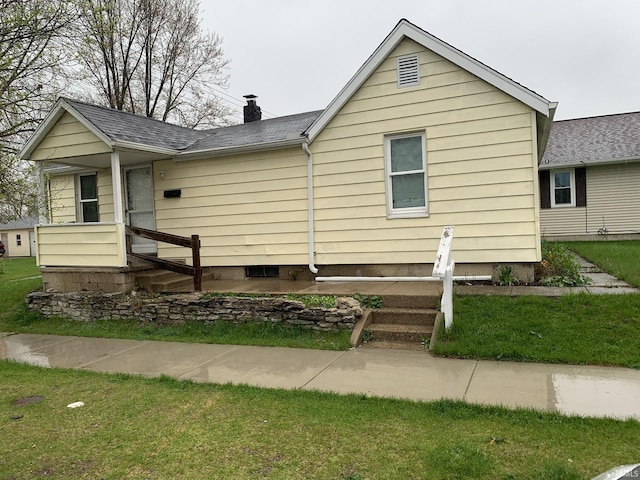 view of front of house featuring roof with shingles, a chimney, and a front lawn