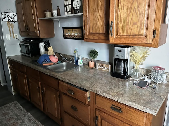 kitchen featuring open shelves, brown cabinetry, and a sink