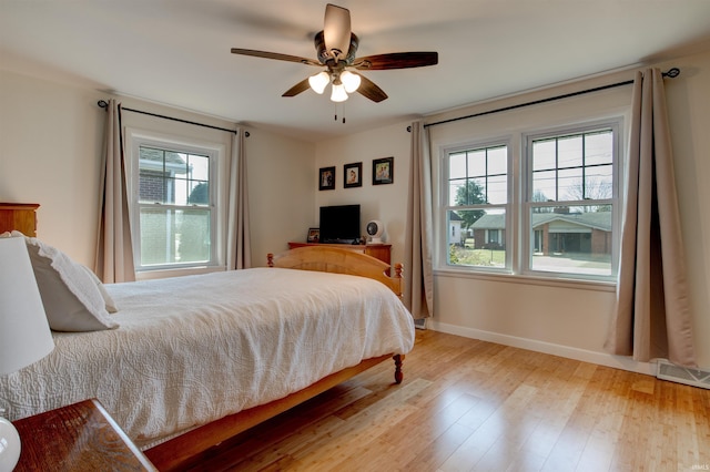 bedroom featuring visible vents, ceiling fan, baseboards, and wood finished floors