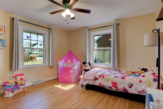 bedroom featuring multiple windows, visible vents, baseboards, and wood finished floors