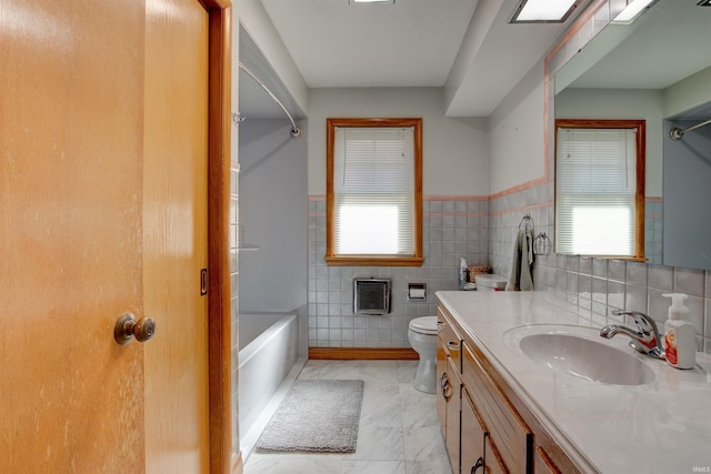 full bath featuring toilet, bathing tub / shower combination, vanity, marble finish floor, and plenty of natural light