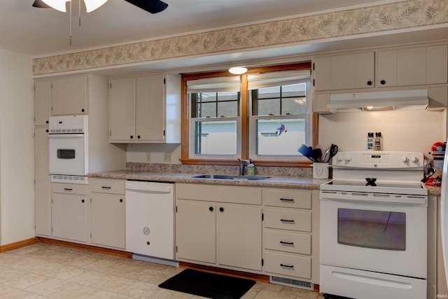 kitchen featuring under cabinet range hood, white appliances, a sink, visible vents, and light countertops