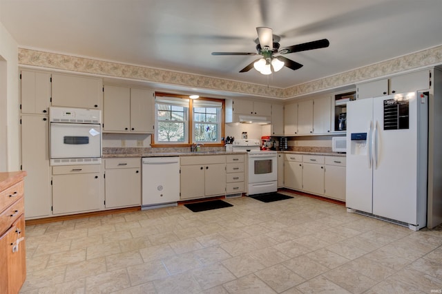 kitchen featuring white appliances, under cabinet range hood, cream cabinetry, and a sink