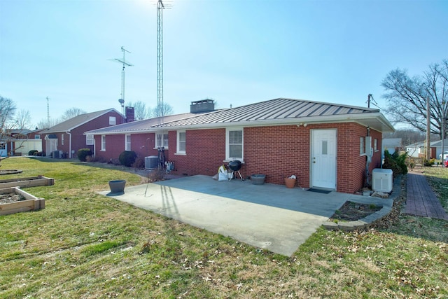 rear view of house with brick siding, a yard, a standing seam roof, metal roof, and cooling unit