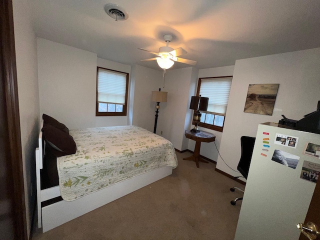 bedroom with carpet, visible vents, ceiling fan, and freestanding refrigerator