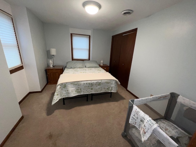 bedroom featuring light carpet, baseboards, multiple windows, and visible vents