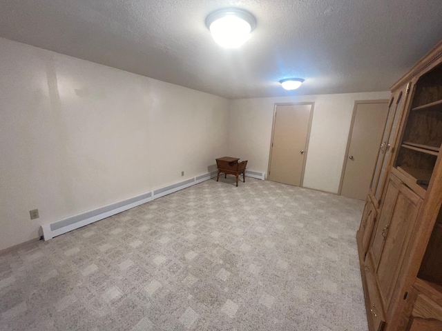 finished basement featuring a baseboard radiator, a textured ceiling, and light colored carpet