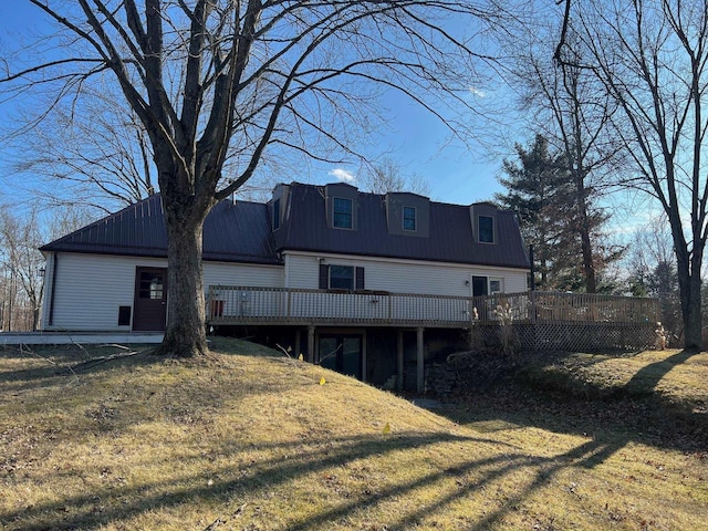 back of property with metal roof, a yard, and a wooden deck