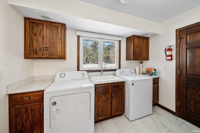 laundry area featuring a sink, baseboards, washer and dryer, marble finish floor, and cabinet space