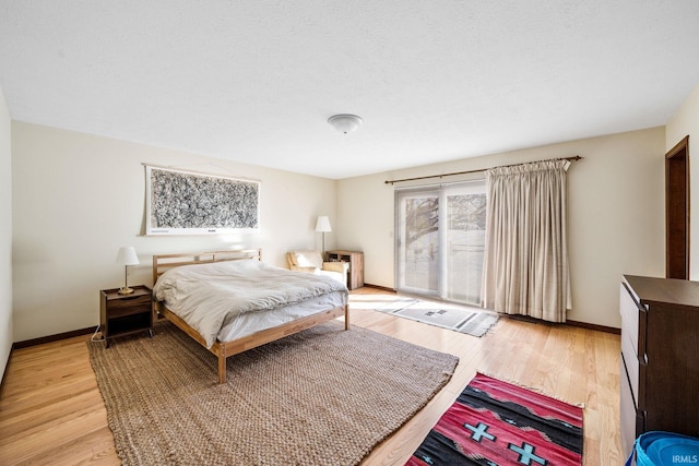 bedroom with light wood-type flooring, a textured ceiling, and baseboards