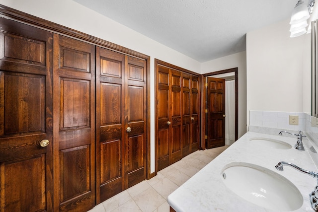 full bath featuring a textured ceiling, double vanity, and a sink