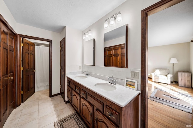 bathroom featuring double vanity, a textured ceiling, decorative backsplash, and a sink