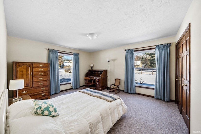 carpeted bedroom featuring a textured ceiling and baseboards