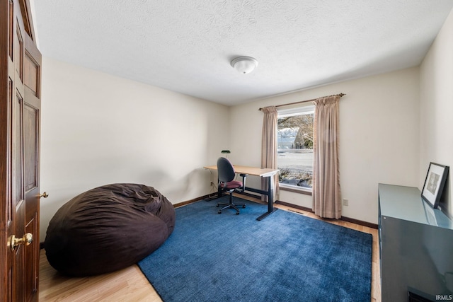 home office with light wood-type flooring, baseboards, and a textured ceiling