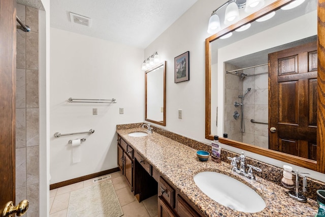 full bath with a textured ceiling, visible vents, a sink, and tiled shower