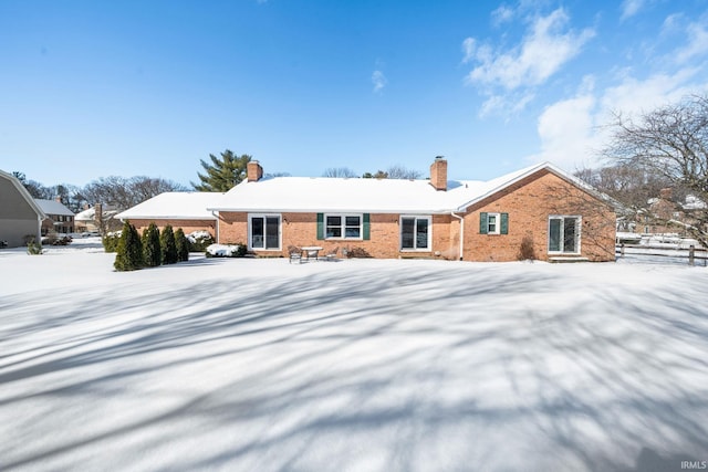 snow covered property featuring brick siding and a chimney