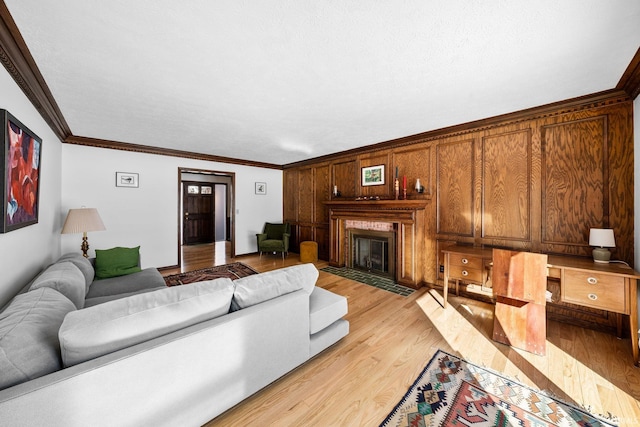 living room featuring light wood-style floors, crown molding, and a fireplace with flush hearth