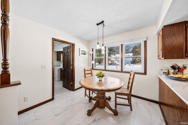 dining space featuring marble finish floor, baseboards, washer / clothes dryer, and a textured ceiling