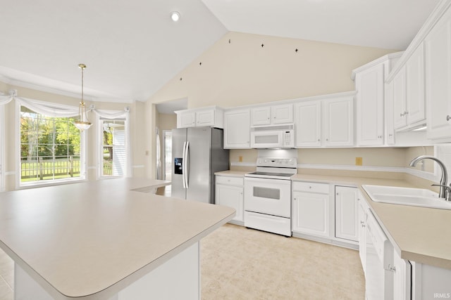 kitchen with white appliances, a sink, white cabinets, light countertops, and a center island