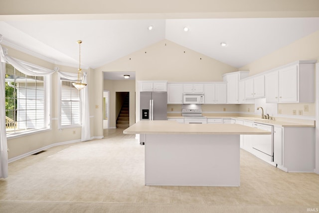 kitchen with a center island, visible vents, white cabinets, a sink, and white appliances