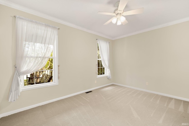 spare room featuring light colored carpet, crown molding, visible vents, and baseboards