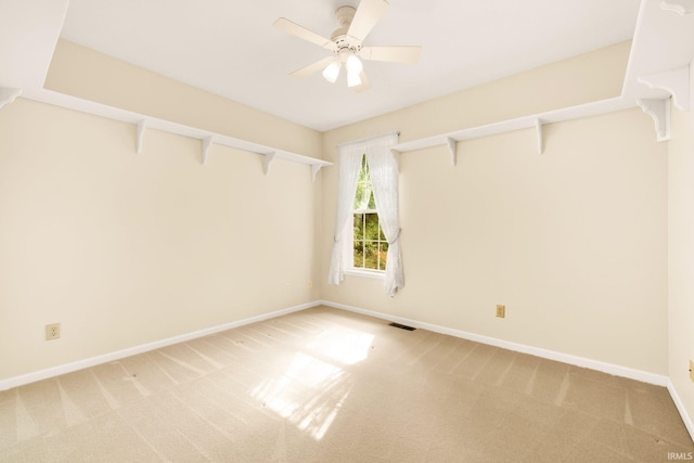 spare room with baseboards, ceiling fan, visible vents, and light colored carpet