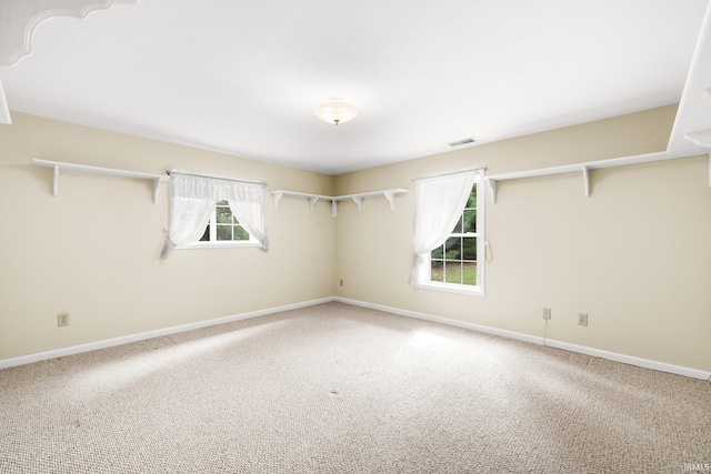 unfurnished room with carpet, visible vents, and baseboards