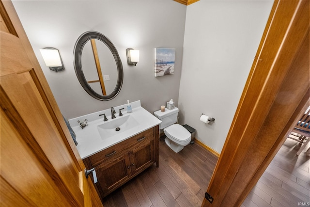 bathroom featuring toilet, vanity, hardwood / wood-style flooring, and baseboards