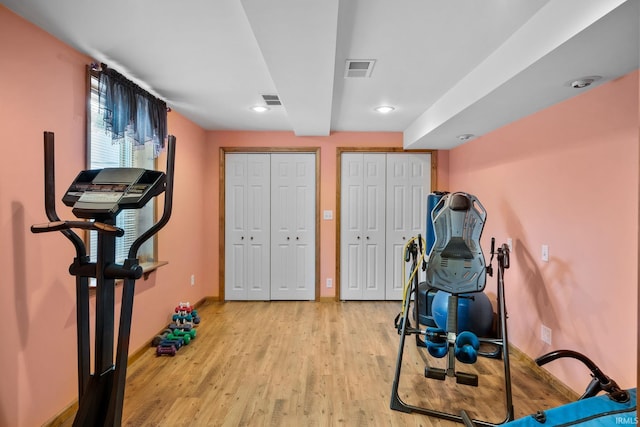 workout area with light wood finished floors, recessed lighting, visible vents, and baseboards