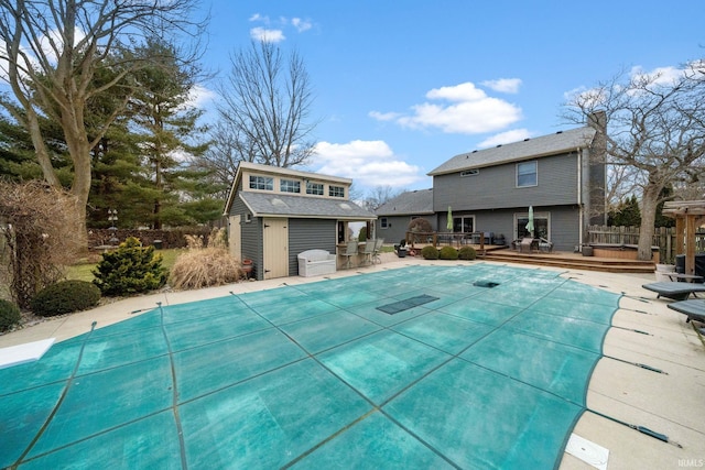 view of pool featuring a fenced in pool, an outbuilding, fence, and a wooden deck