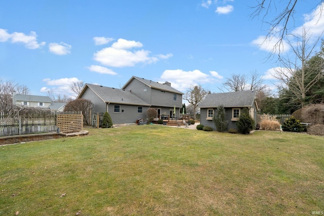 rear view of property featuring a yard, fence, and an outbuilding