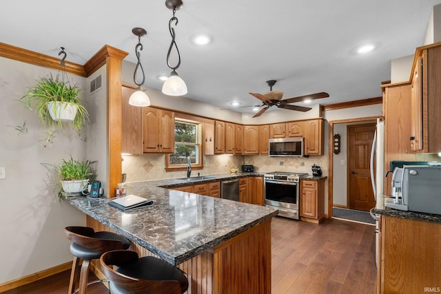 kitchen featuring dark wood-style flooring, visible vents, appliances with stainless steel finishes, a sink, and a peninsula