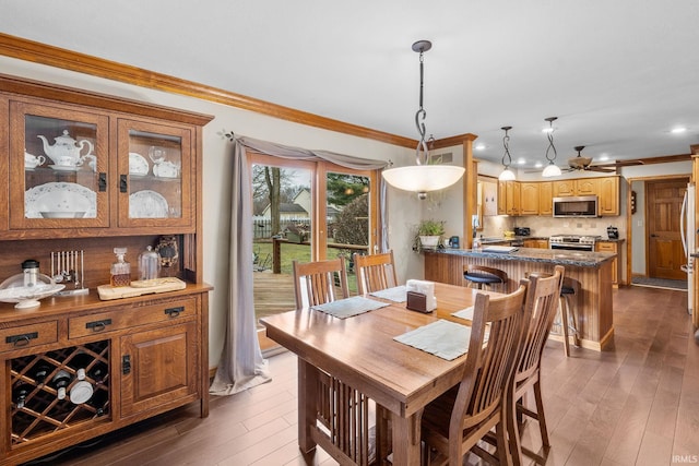 dining space with ornamental molding and wood finished floors