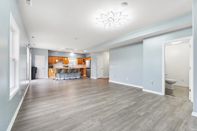 unfurnished living room with recessed lighting, baseboards, visible vents, and light wood finished floors