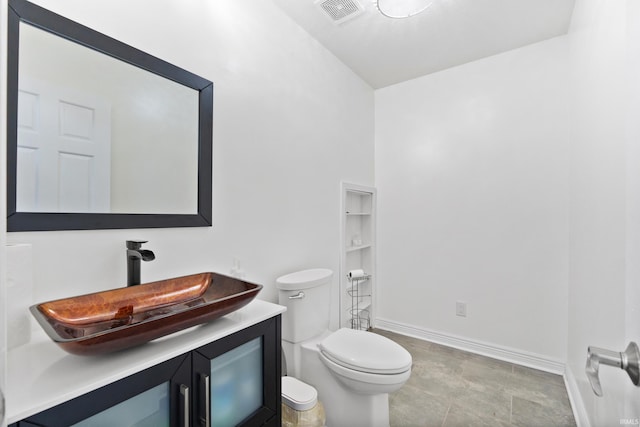 bathroom with toilet, vanity, visible vents, and baseboards