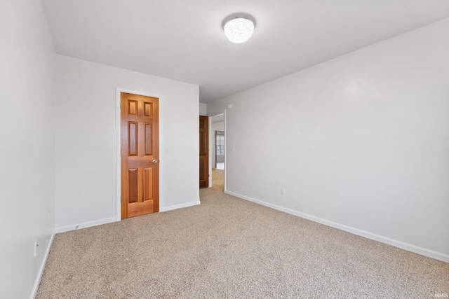 spare room featuring carpet flooring and baseboards