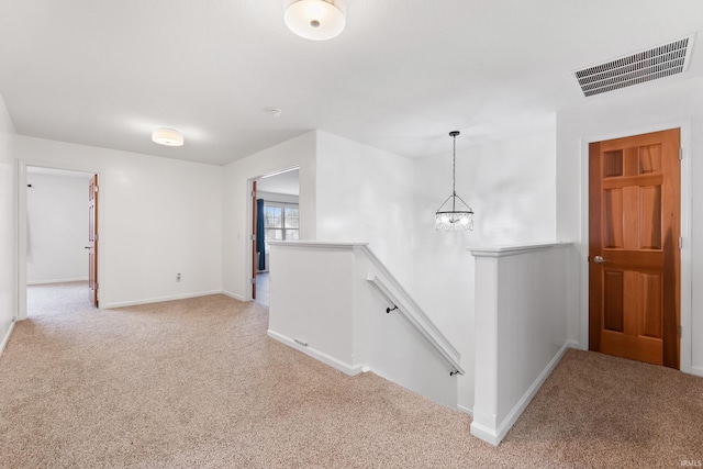 hall with visible vents, baseboards, an upstairs landing, and light colored carpet