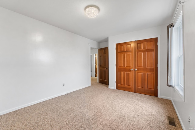 unfurnished bedroom featuring carpet floors, baseboards, visible vents, and a closet