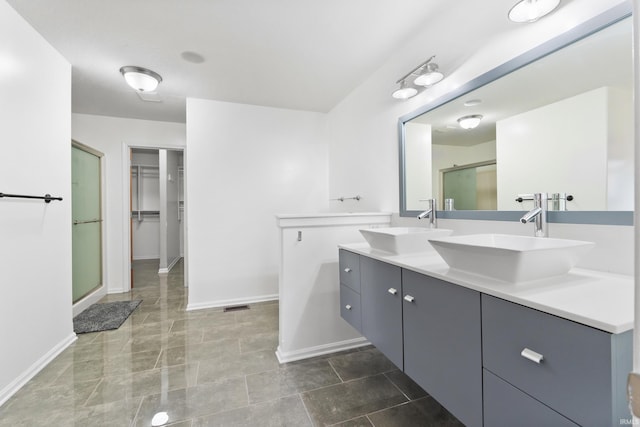 full bath featuring double vanity, a stall shower, a sink, and baseboards