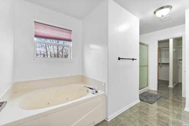 full bathroom featuring visible vents, baseboards, a shower stall, a whirlpool tub, and a walk in closet