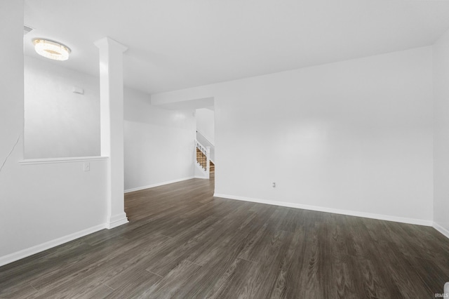 unfurnished living room featuring dark wood-style floors, baseboards, and stairs