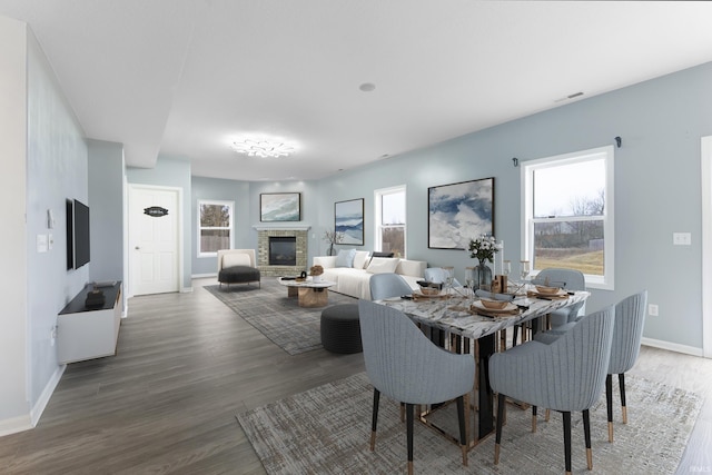 dining area with visible vents, a fireplace, baseboards, and wood finished floors