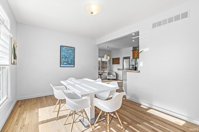 dining space featuring light wood-style floors, baseboards, and visible vents