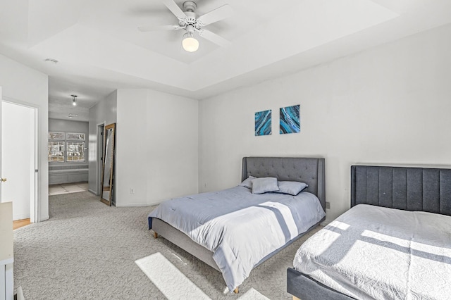 carpeted bedroom featuring a tray ceiling, ceiling fan, and baseboards