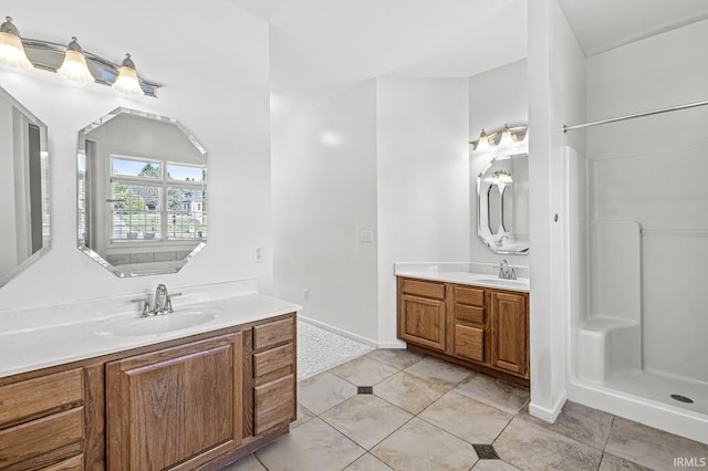 bathroom featuring a shower, two vanities, tile patterned flooring, and a sink