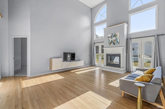 living room with plenty of natural light, baseboards, wood finished floors, and a glass covered fireplace